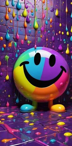 a smiley face balloon sitting in front of a wall with drops of paint on it