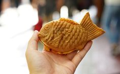 a person holding up a cookie shaped like a fish