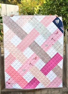 a pink and white quilt hanging on a fence