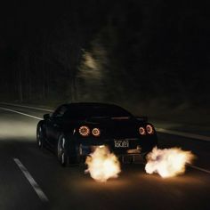 a black sports car driving down the road with flames coming out of it's tires