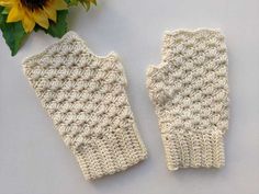 two white crocheted gloves next to a sunflower