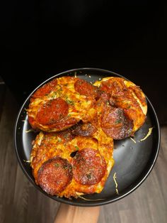 two pepperoni pizzas sitting on top of a black plate