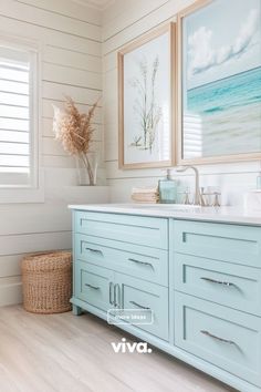 a bathroom with two pictures on the wall and a blue vanity in front of it