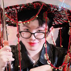 a man with glasses and a hat on his head holding an umbrella over his head