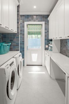 a washer and dryer in a white laundry room with blue tile on the walls