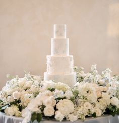 a wedding cake sitting on top of a table covered in white flowers and greenery