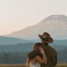 a man and woman embracing in front of a mountain