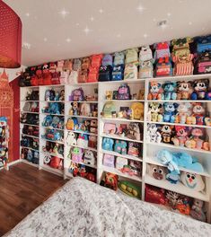 a room filled with lots of stuffed animals on shelves next to a bed and wooden floor