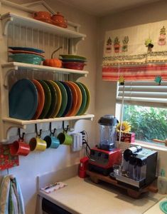 the kitchen has many plates and cups on the shelves