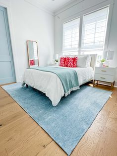 a bedroom with a bed, dresser and mirror on the wall next to two windows