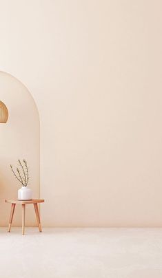 an empty room with a table, lamp and vase on the floor in front of it