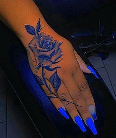 a woman's hand with blue nails and a rose tattoo