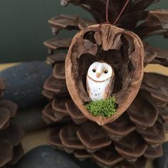 an owl ornament hanging from a pine cone