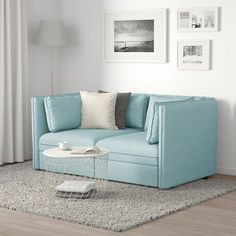 a blue couch sitting on top of a rug in a living room next to a window