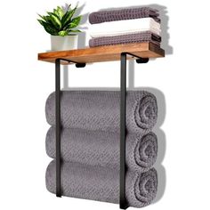 a towel rack with three folded towels and a potted plant