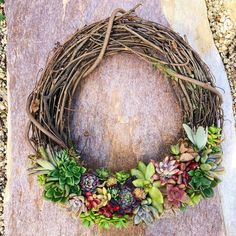 a wreath with succulents is sitting on a rock