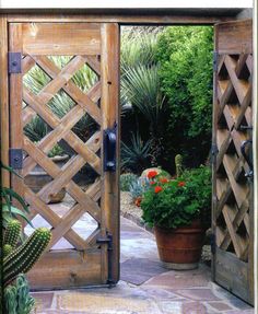 an open wooden gate with potted plants and cacti