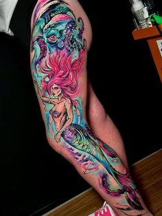 a woman's leg with colorful tattoos on it and an image of a mermaid