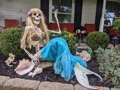 a skeleton sitting on the ground in front of a house with plants and other decorations