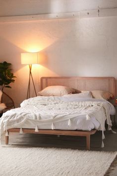 a bed with white sheets and pillows in a room next to a lamp on the wall