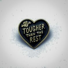 a black and gold heart shaped pin with the words tougher than the rest on it