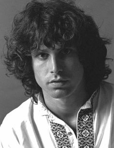 a black and white photo of a young man with curly hair wearing a collared shirt