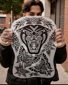 a man holding up a paper cutout with an animal design on it