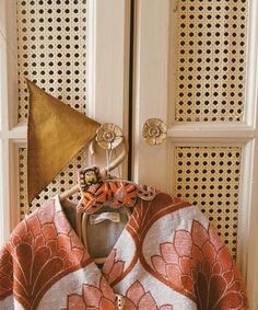 an orange and white shirt with a gold triangle on it's head sitting in front of a door