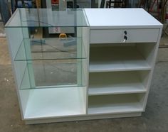 a white cabinet with glass shelves on the front and bottom, sitting in a warehouse