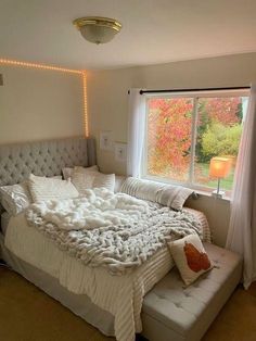 a bedroom with a large bed covered in white blankets and pillows, next to a window