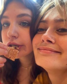 two young women are eating some food together