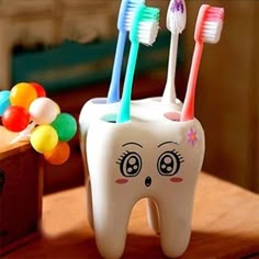 a toothbrush holder with three different colored toothbrushes in it and a wooden box next to it