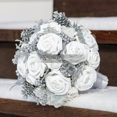 a bridal bouquet sitting on top of a wooden bench in front of snow covered stairs