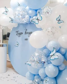 blue and white balloons with butterflies are on display in a room that is decorated for a baby's first birthday