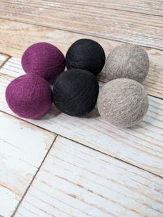 four balls of wool sitting on top of a wooden floor next to eachother