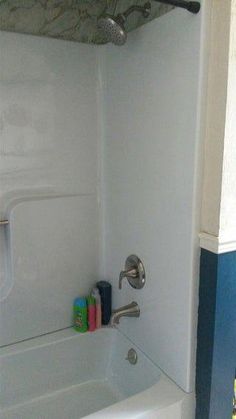 a bathroom with a bathtub, shower head and toilet paper dispenser