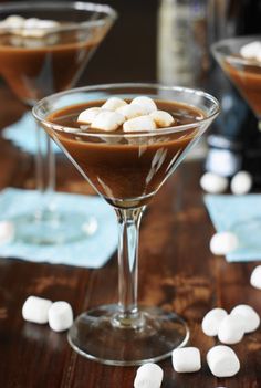 two martini glasses filled with chocolate pudding and marshmallows on a wooden table