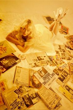 a woman laying on top of a bed covered in newspapers