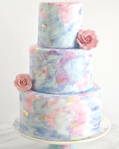 a three tiered cake with pink and blue icing on it's side