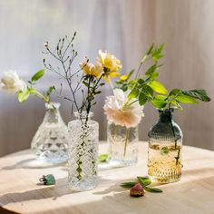 three vases with flowers in them sitting on a table