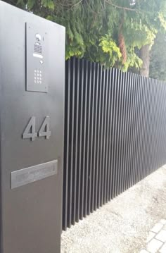 a black metal mailbox sitting next to a fence with numbers on the front and back