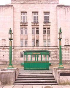 a green trolley car sitting in front of a tall building