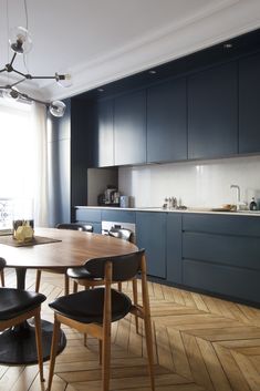 a dining room table and chairs in front of an open kitchen area with wood flooring