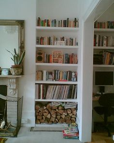 a living room filled with lots of books next to a fire place and a fireplace