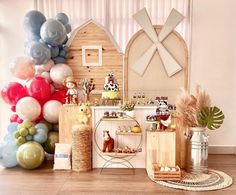 an assortment of balloons and decorations on display in front of a wooden wall with a barn