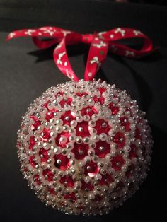 a red and white ornament hanging on a black surface with a red ribbon