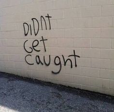 graffiti is spray painted on the side of a white brick wall that reads, didn't get caught