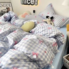 an unmade bed with blue and white checkered sheets, pillows and stuffed animals