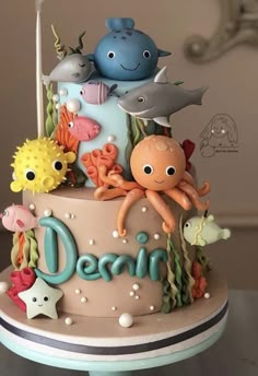 a three tiered cake decorated with sea animals and the word ocean on it's side