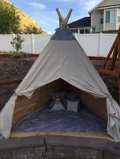 a teepee tent sitting on top of a brick wall next to a wooden fence